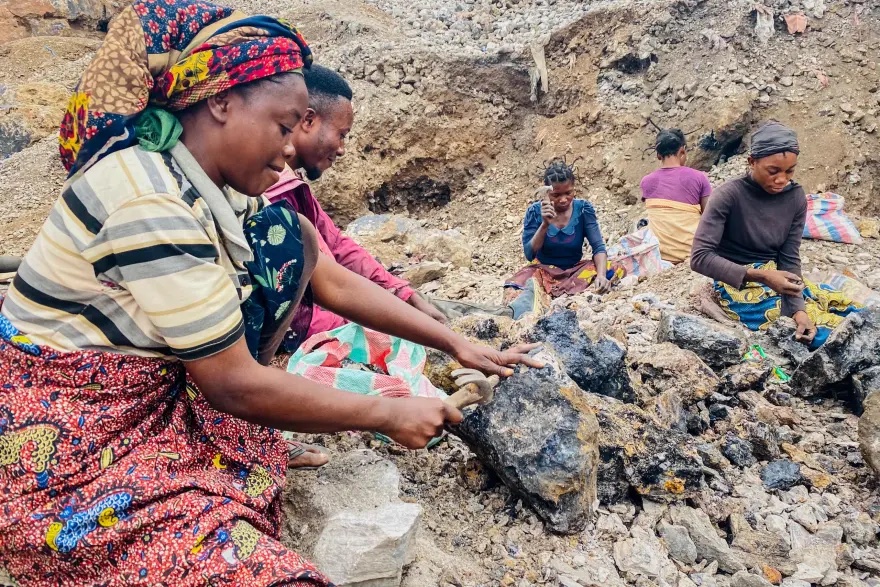 Miners wearing casual clothes sitting down breaking rocks with a simple tools