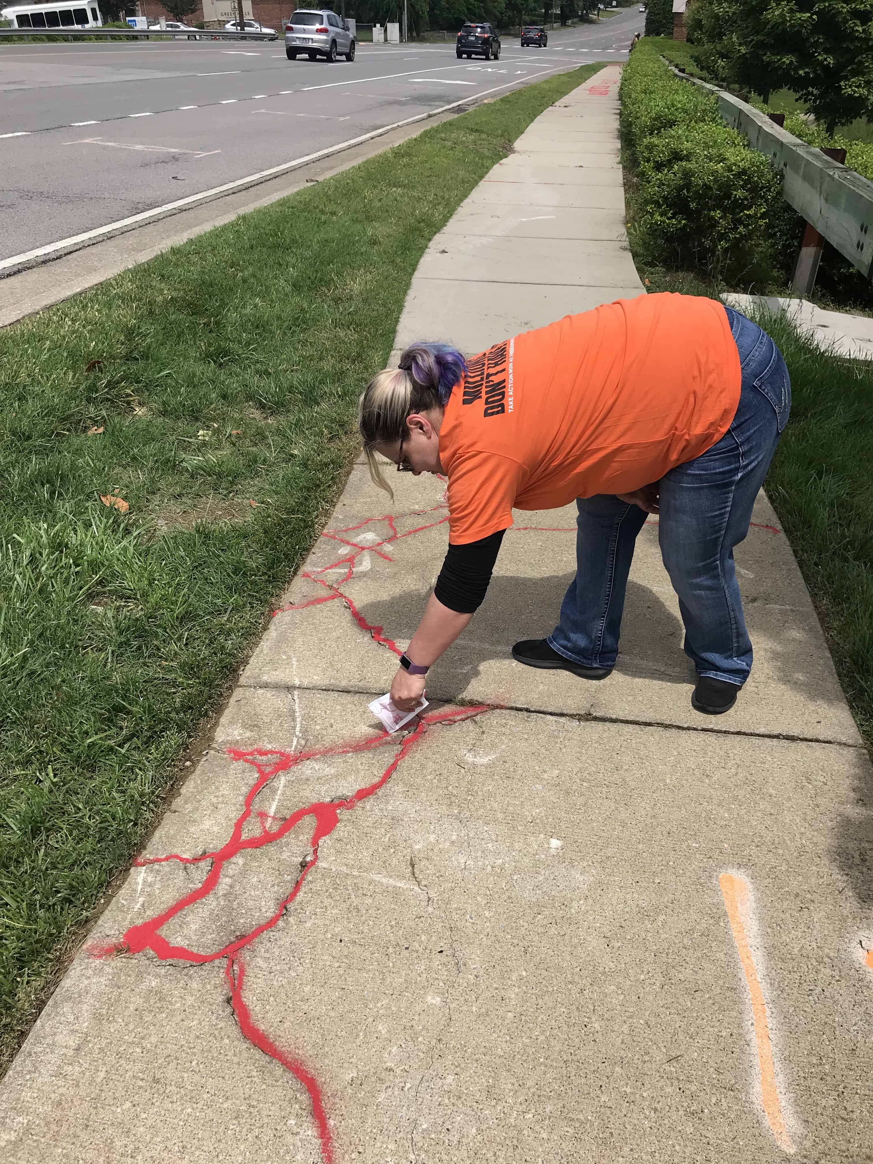 katina french pouring red sand into sidewalk