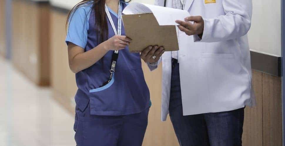 Dos profesionales de la salud mirando notas en un portapapeles