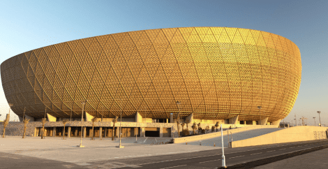 Outside of the Lusail stadium, strikingly gold against a blue sky