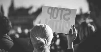 black and white image of woman holding up a sign that reads stop Putin