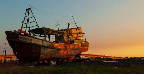 rusted old ship beached at sunset