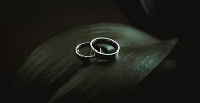 Zwei silberne Ringe auf einem Blatt mit dunklem Hintergrund, die die Dunkelheit der Zwangsheirat von Kindern darstellen