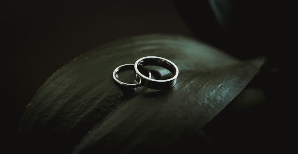 Two silver rings on a leaf with dark background representing the darkness of forced child marriage