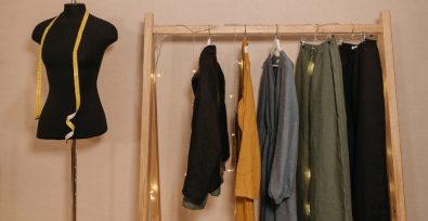 five pieces of clothing on a rack with a measuring mannequin to the left.