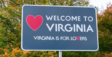 Cartel azul que dice "Bienvenido a Virginia: Virginia es para los amantes" detrás de un fondo de árboles verdes.