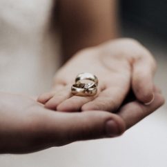 Two hands on top of each other, palms up, with silver rings in them.
