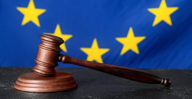 Im Hintergrund die EU-Flagge und davor ein Gerechtigkeitshammer