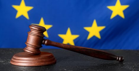 The EU flag in the background and a justice hammer in front