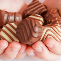 Two hands holding a bunch of chocolate candies