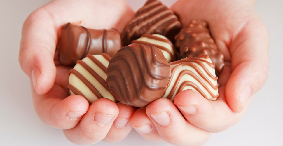 Two hands holding a bunch of chocolate candies