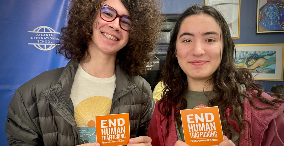 Two teenagers holding up "end human trafficking" cards