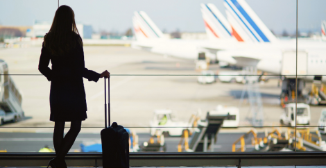 woman silhouette at airport in front of window looking out at planes