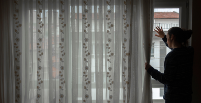 woman looking out window in dark room