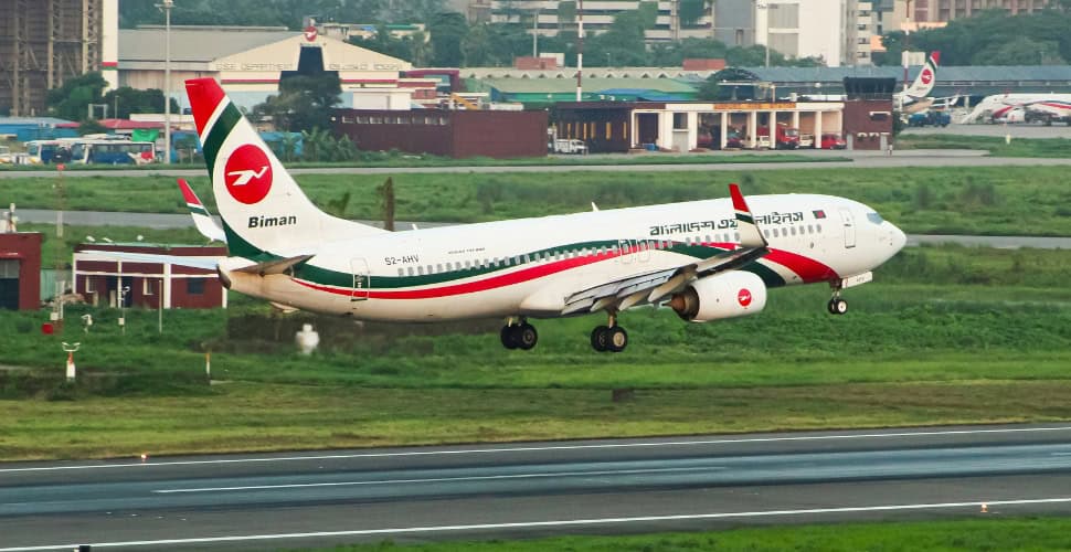 a plane standing stationary on grass along a runway
