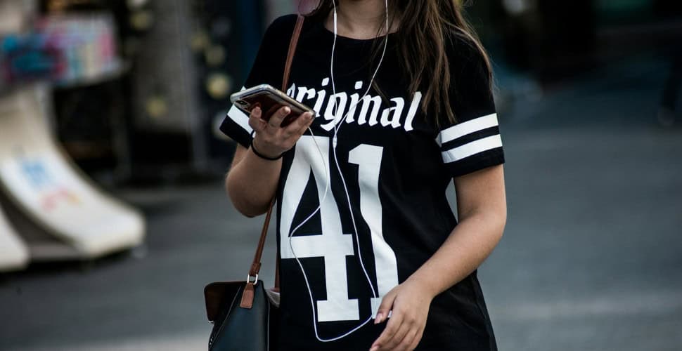 Teen girl walking down the road listening to music on ear buds
