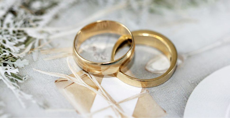Two gold wedding rings interlinked on white lace