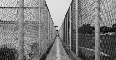 black and white path through barbed wire fences on either side
