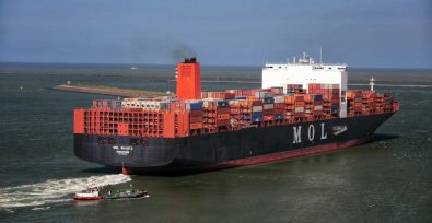 shipping container heading to port with a smaller ship following