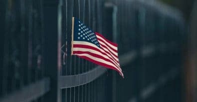 Eine amerikanische Flagge weht an einem Metallzaun.